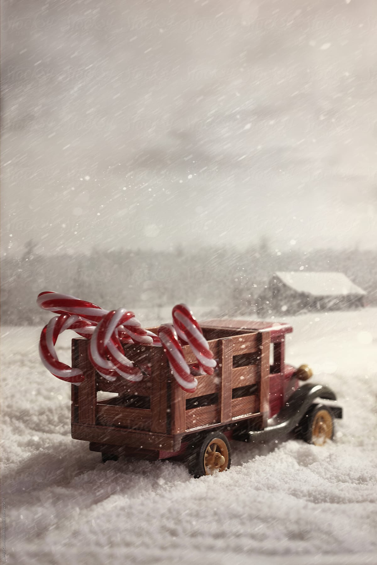Small toy truck with candy canes in snow