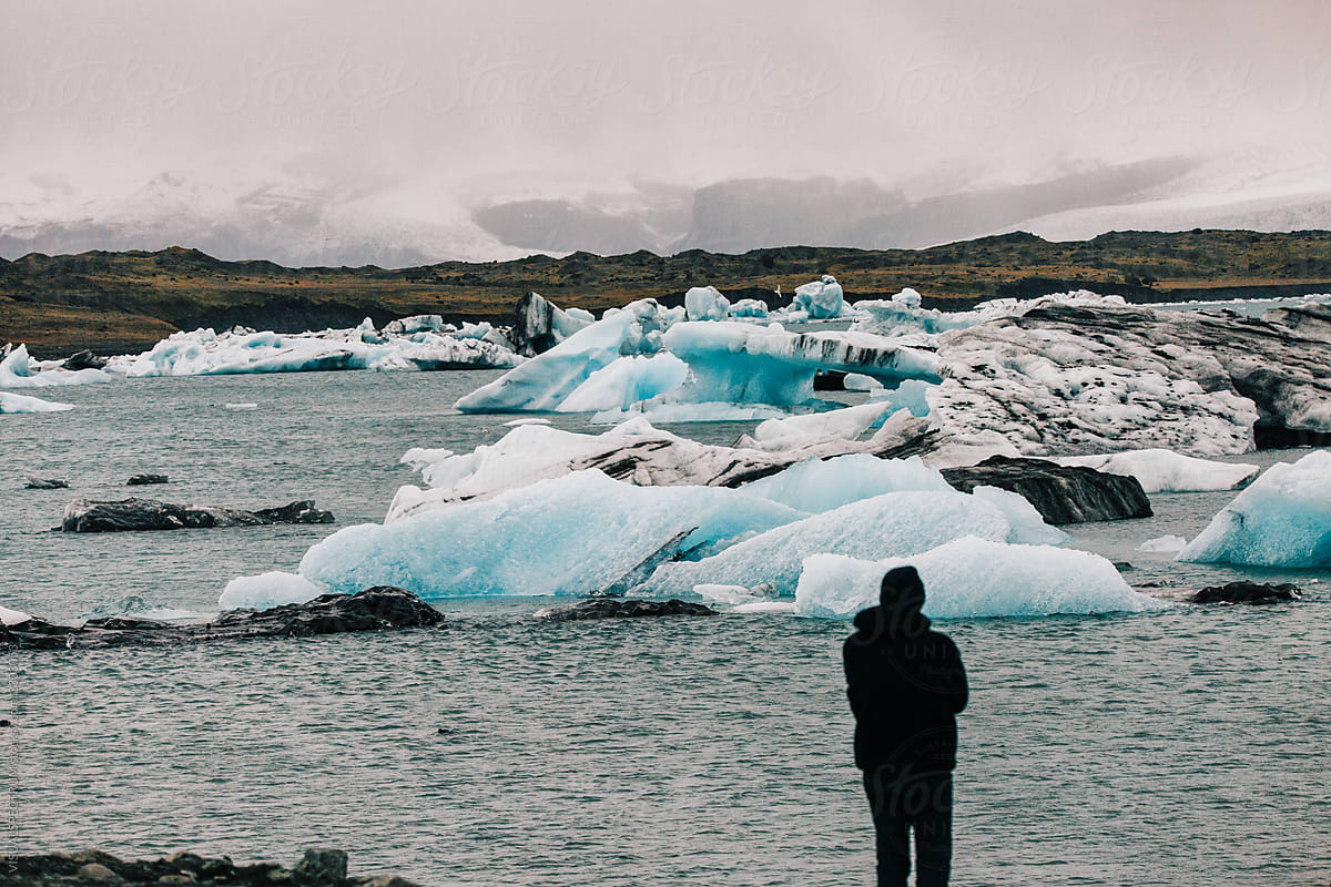 Iceland Tourism - Anonymous Man Looking at Floating Icebergs in Lagoon