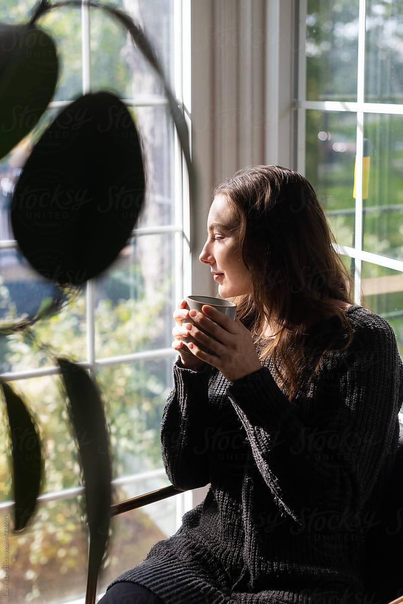 Woman relaxing by window with coffee