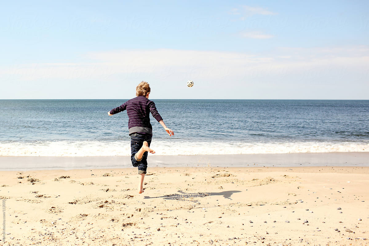 Boy performing a soccertrick on the beach