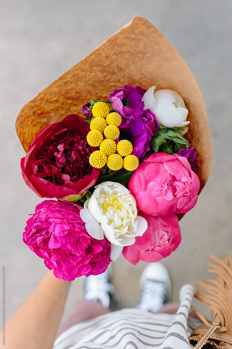 A first person view of someone holding a peony arrangement