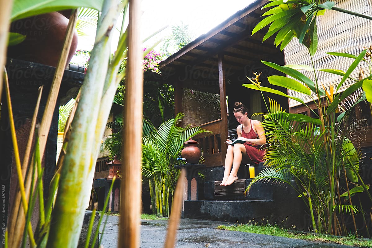 A young woman writing in her diary at a cabin in the jungle
