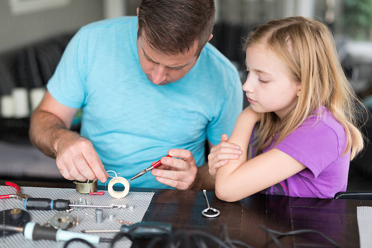 Man Repairing AC Appliance Motor With Little Girl