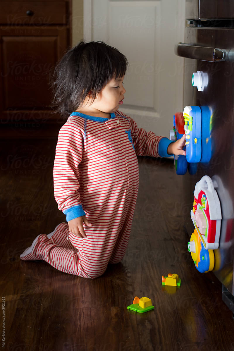 Young girl in pajamas playing with refrigerator magnets