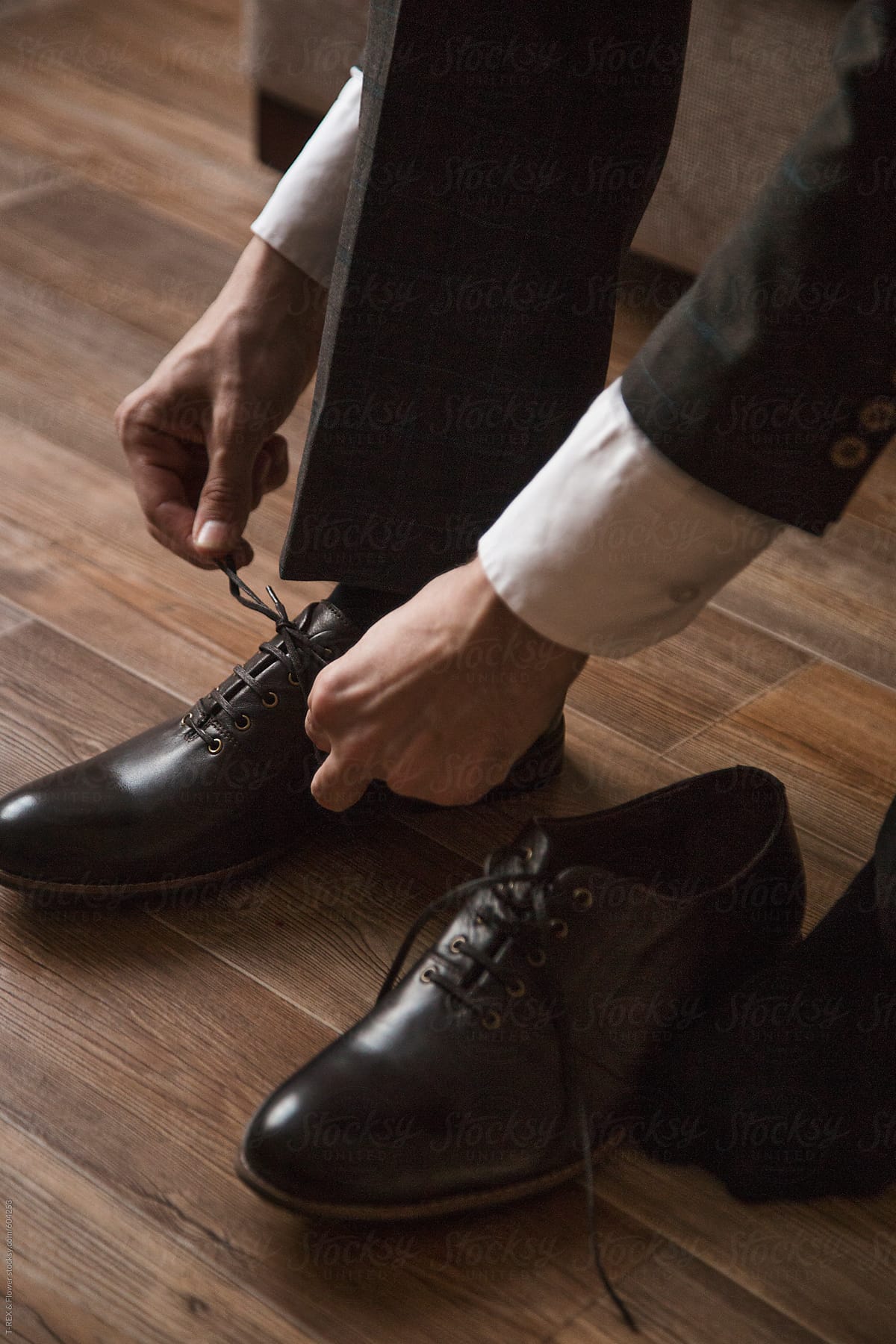 Man's hands tie brown shoe