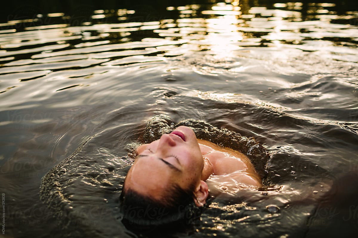 A young man floats on his back in a lake on a summer day