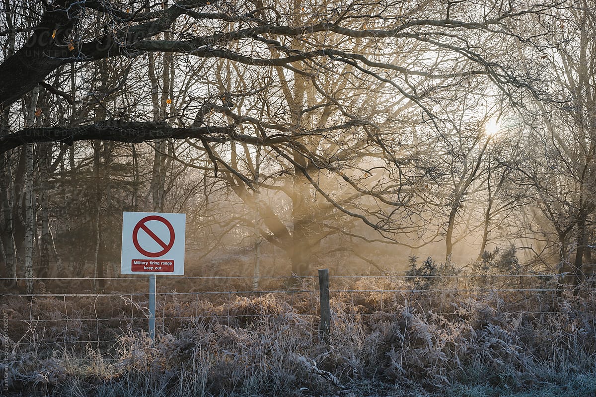 Sunlight through mist and military firing range sign.