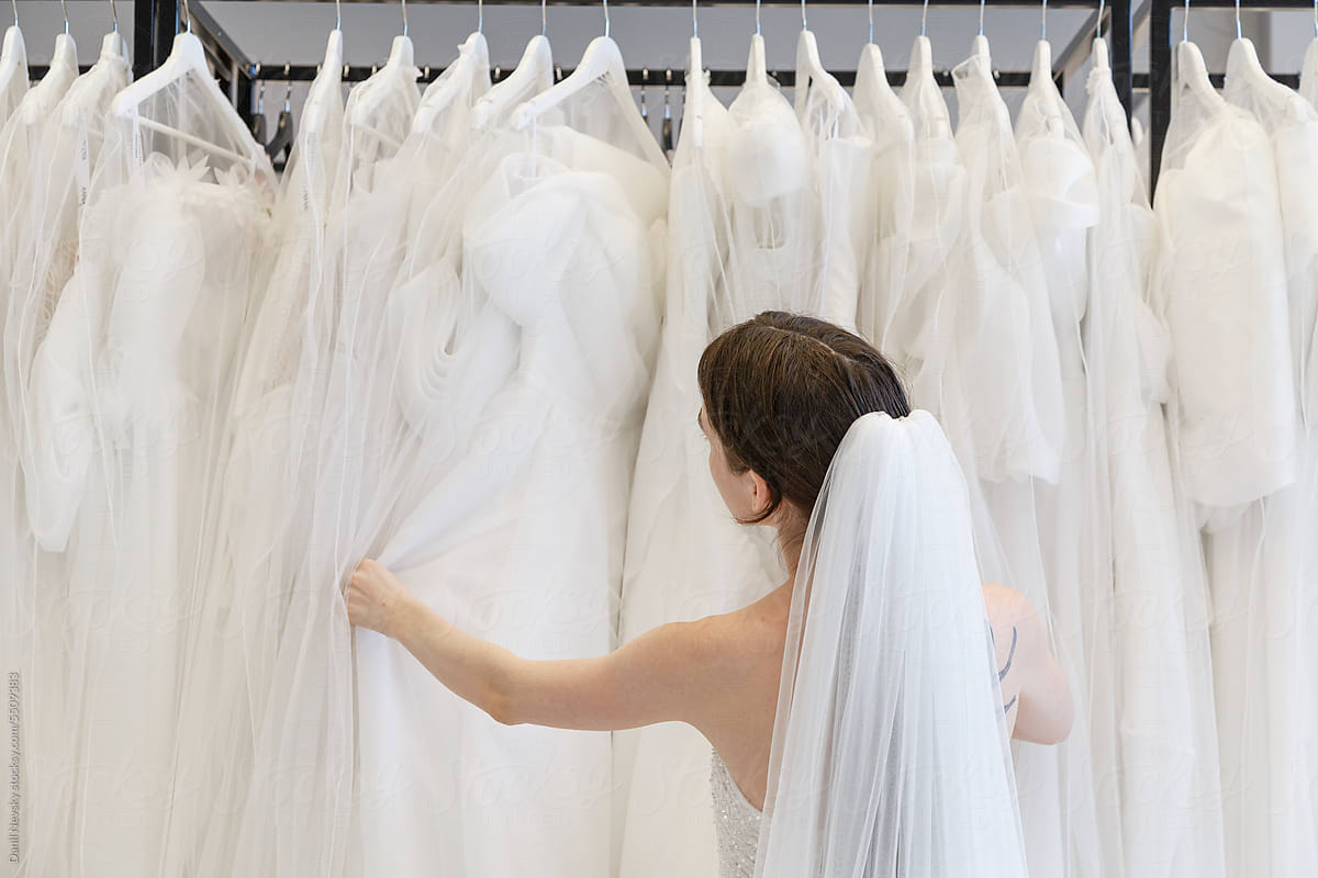 Bride choosing white weeding dress in showroom