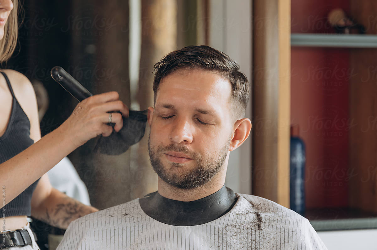 Crop barber removing hair from clients face