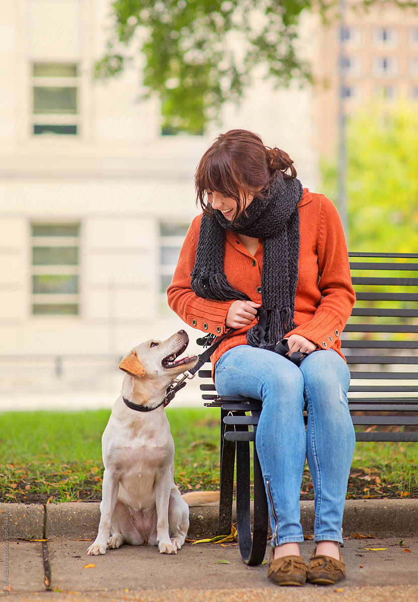 Retro styled woman sitting with Dog on Park Bench