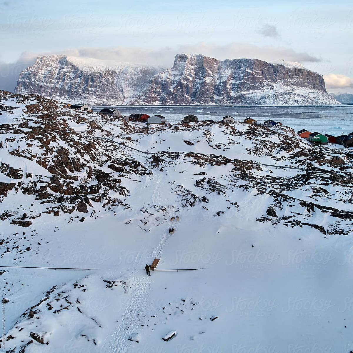 Mushing Greenlandic dog sled up hill in Uummannaq, midwinter
