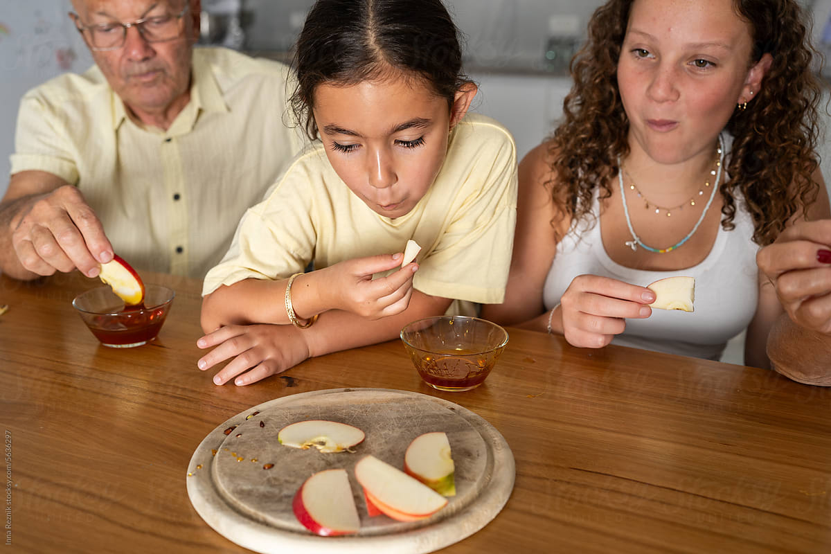 Grandfather and Granddaughters Savoring Honey-Drizzled Apple Slices.