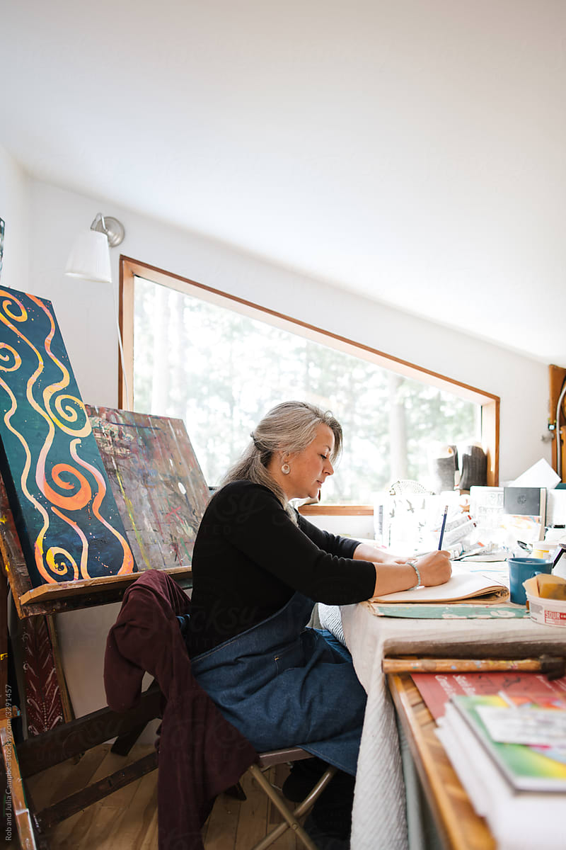Mature woman working and playing with art in her home loft studi