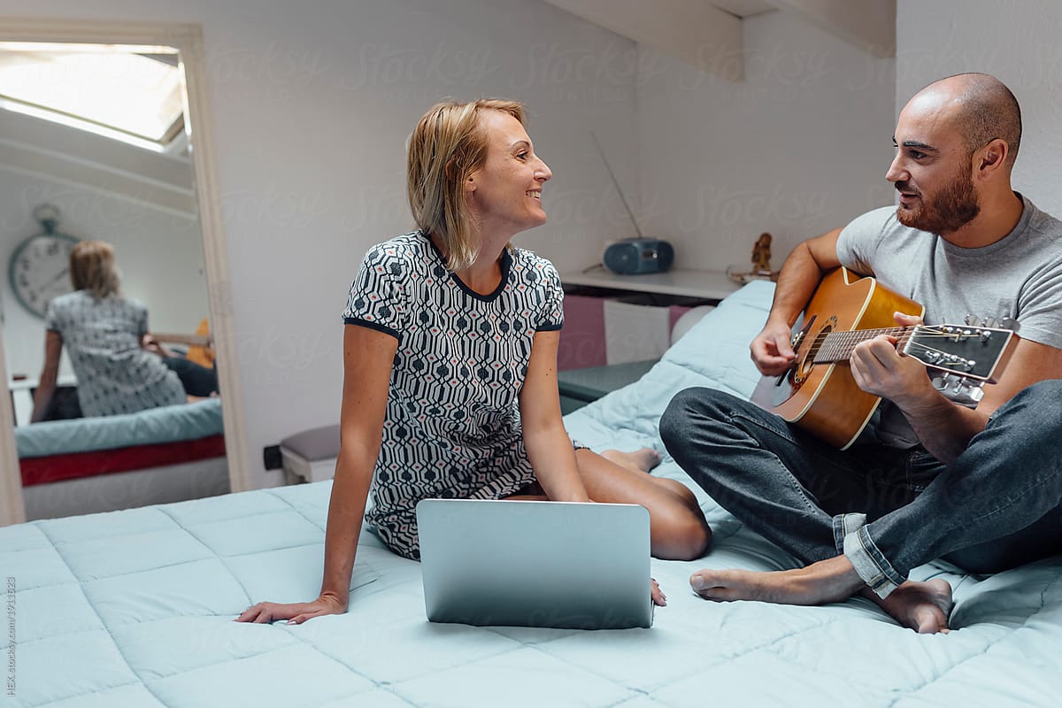 Adult Couple Spending Time In Their Bedroom Using A Laptop And Playing