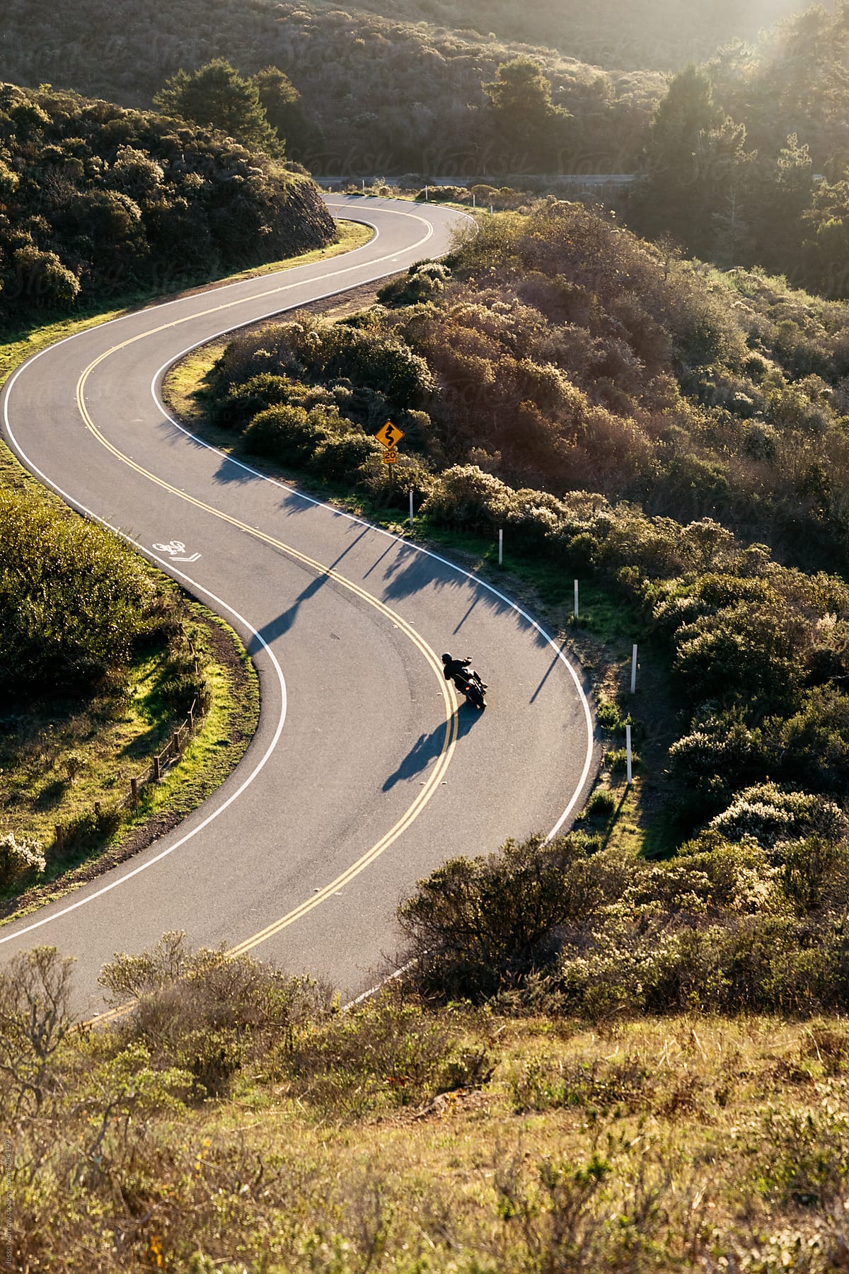 young men ride motorbikes on winding roads in california countryside