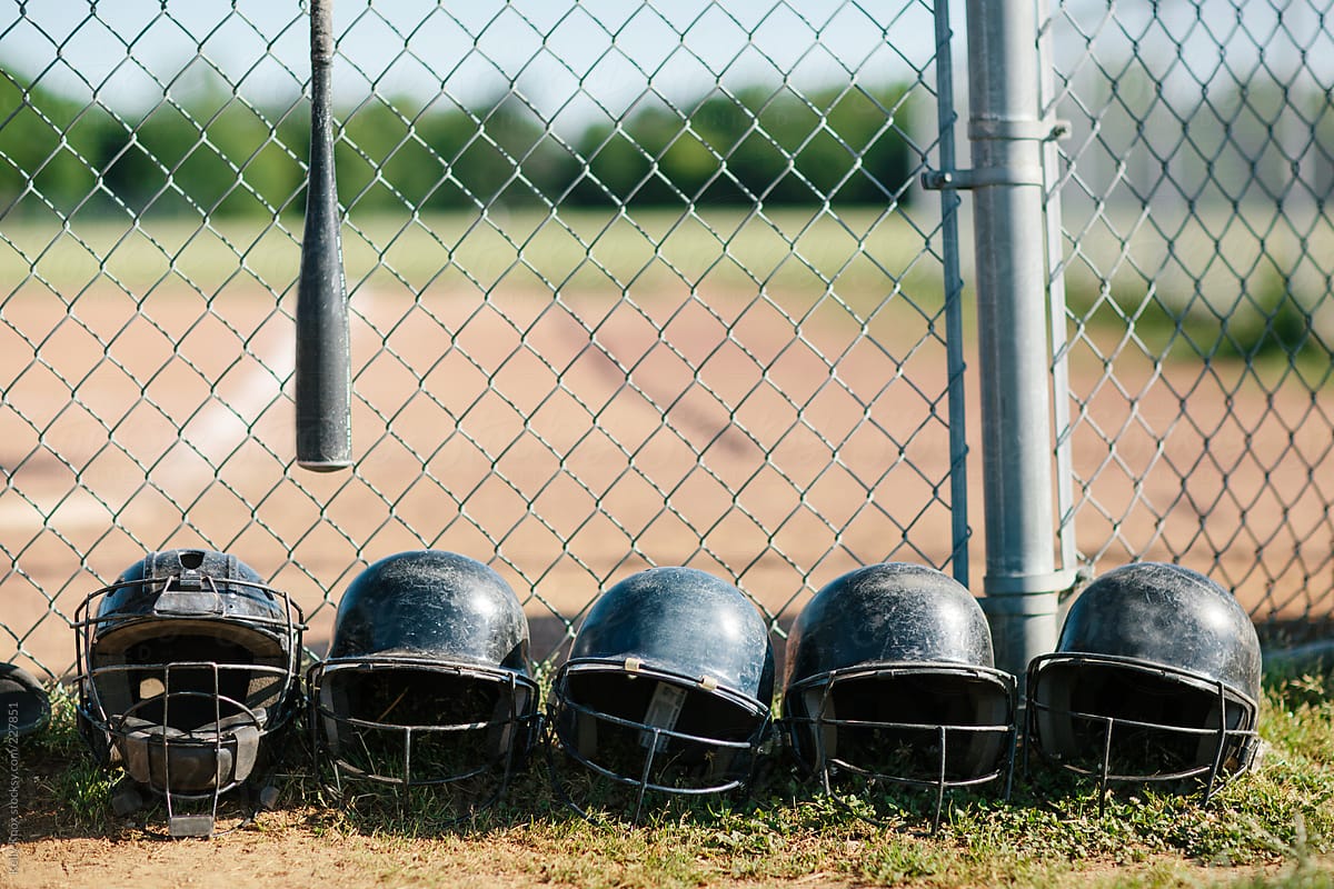 baseball helmets in a row along a fence