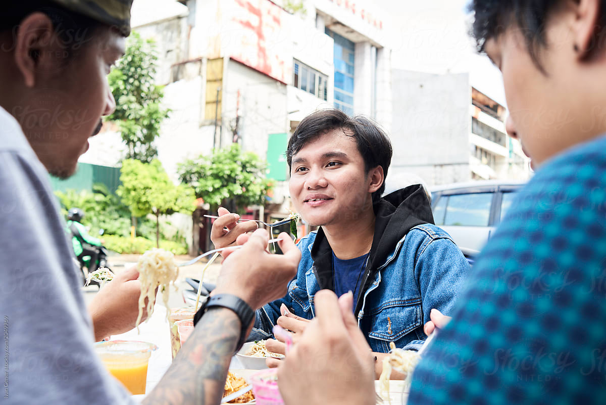 Asian friends eating street food outside