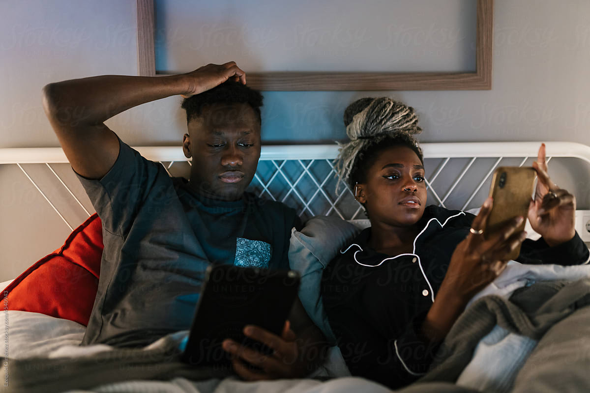 African American couple using devices before sleep