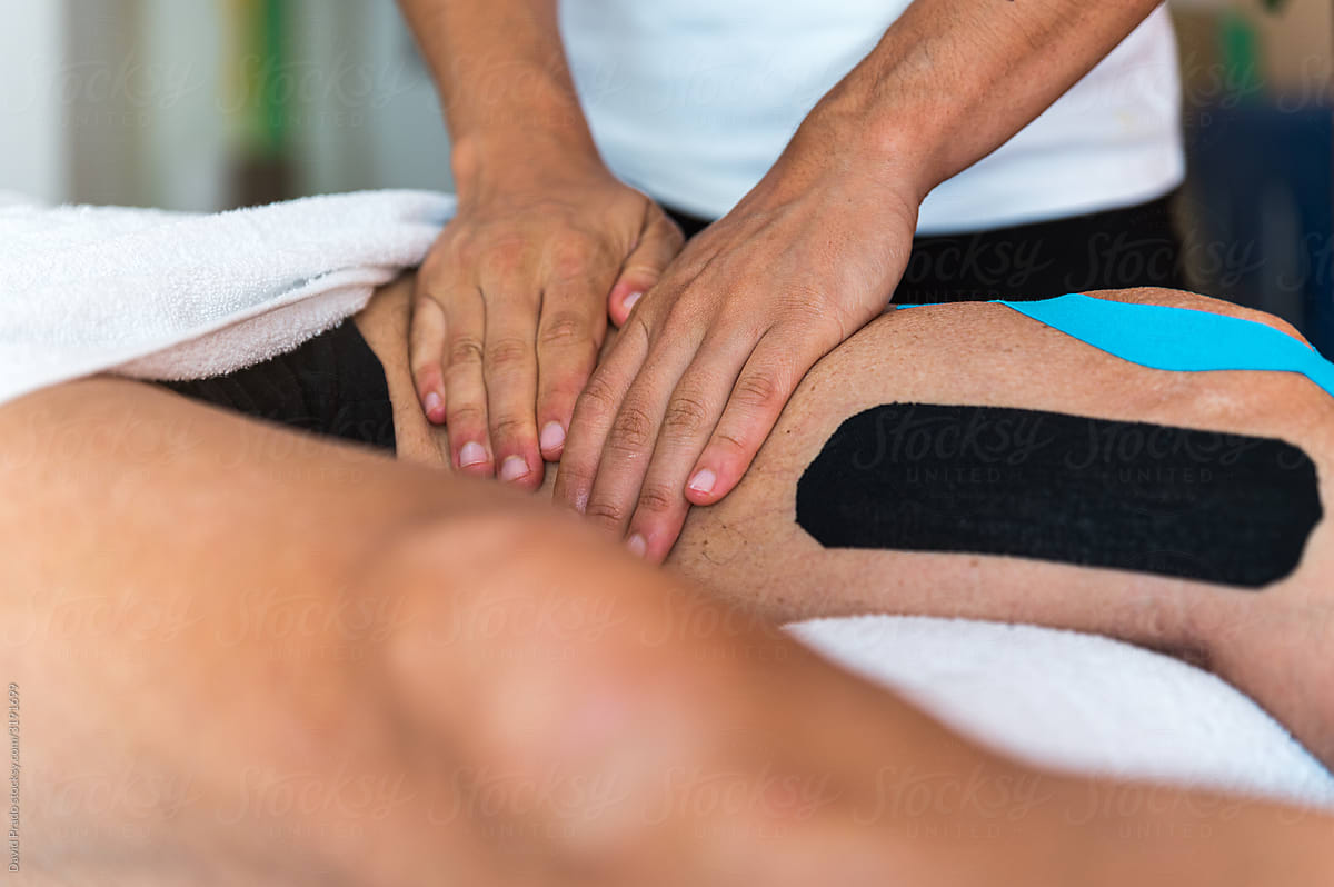 Crop therapist massaging knee of patient