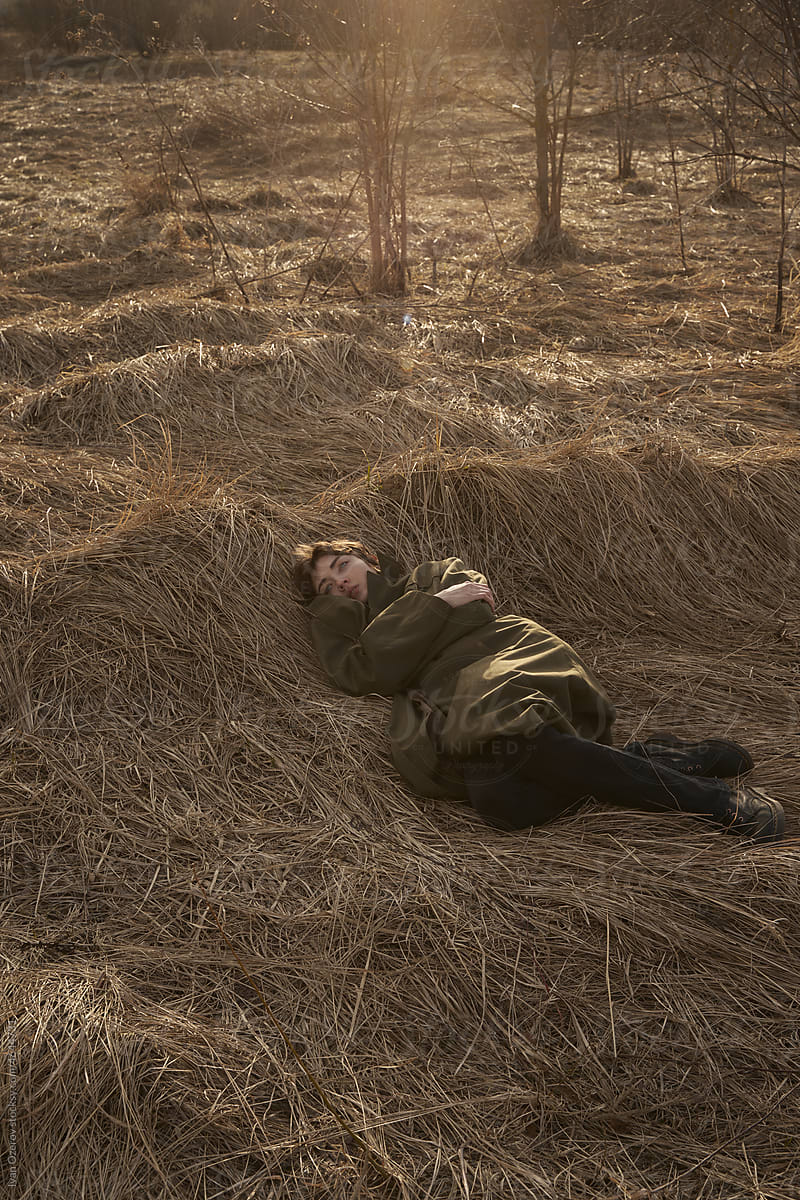 Woman in coat lying on dry grass in field