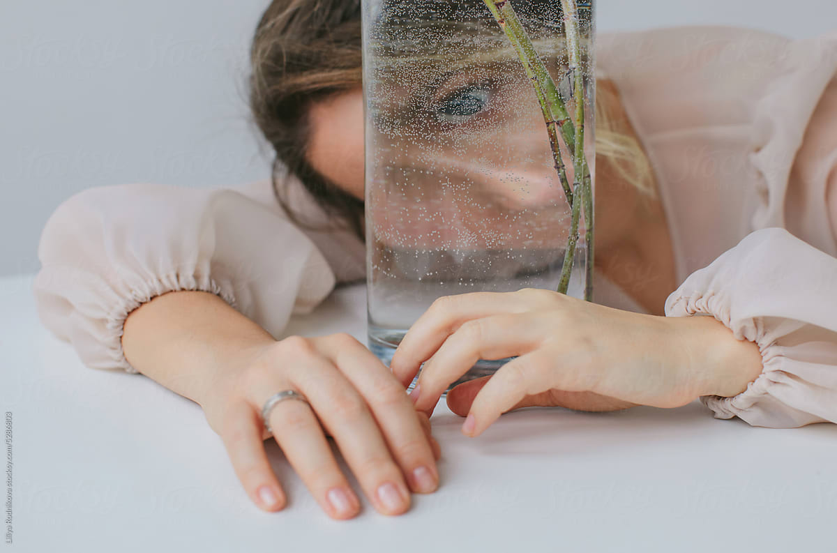 Young woman looking at camera through glass vase