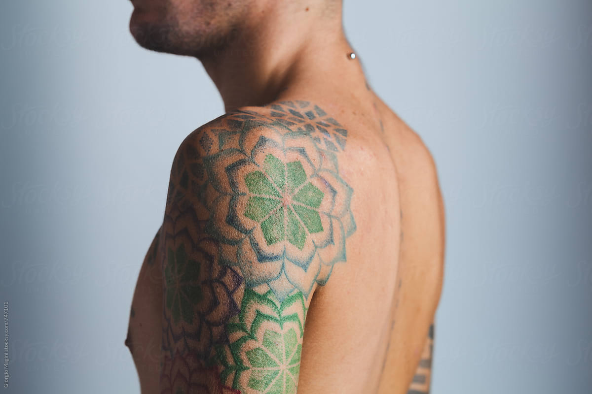 Young Man With Tattoos Flowers On The Shoulder