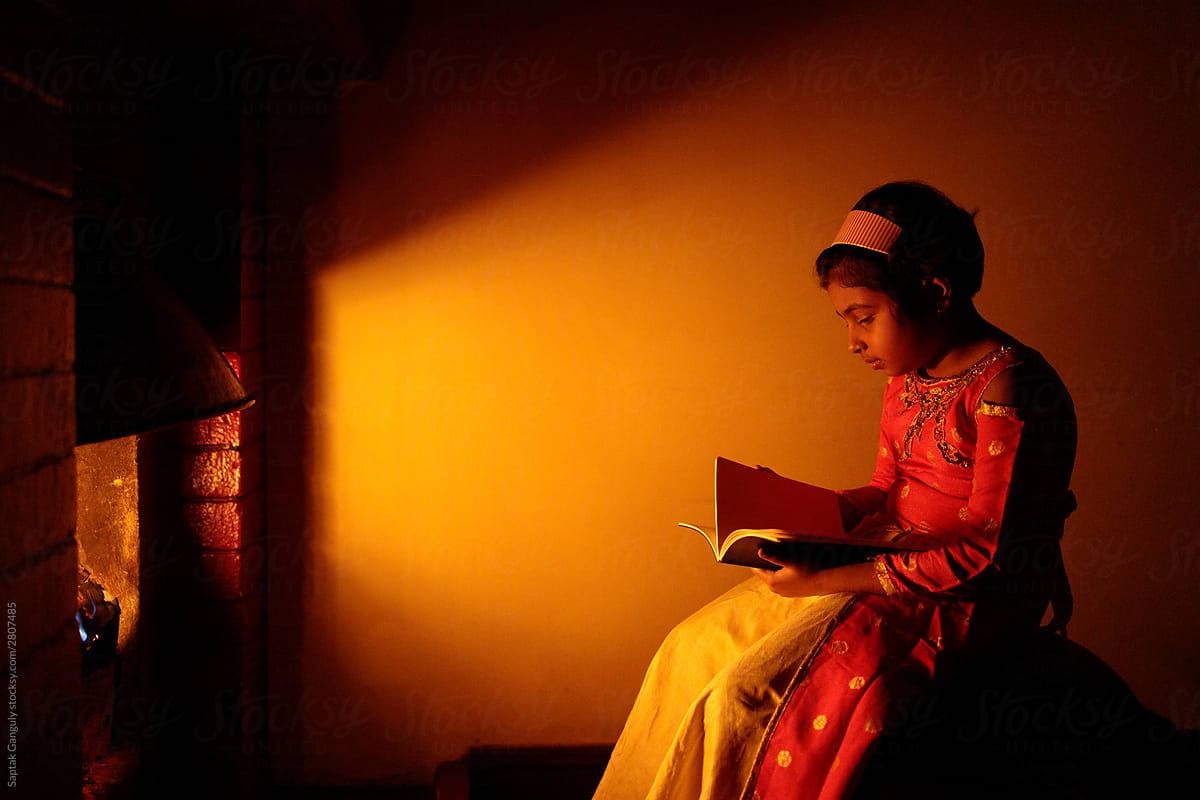 Little girl sitting by the fireplace with a book