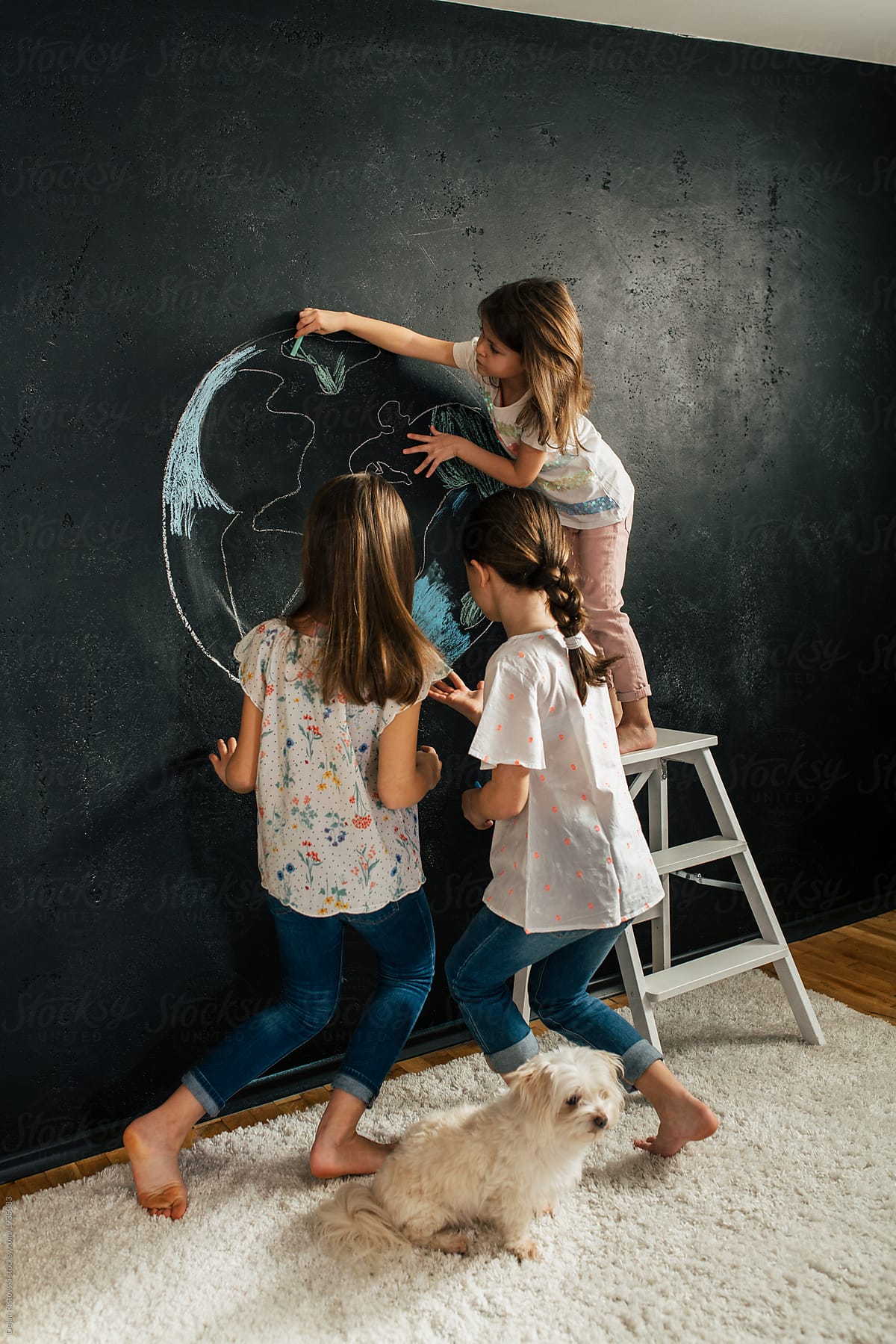 Young girl drawing planet earth on a blackboard