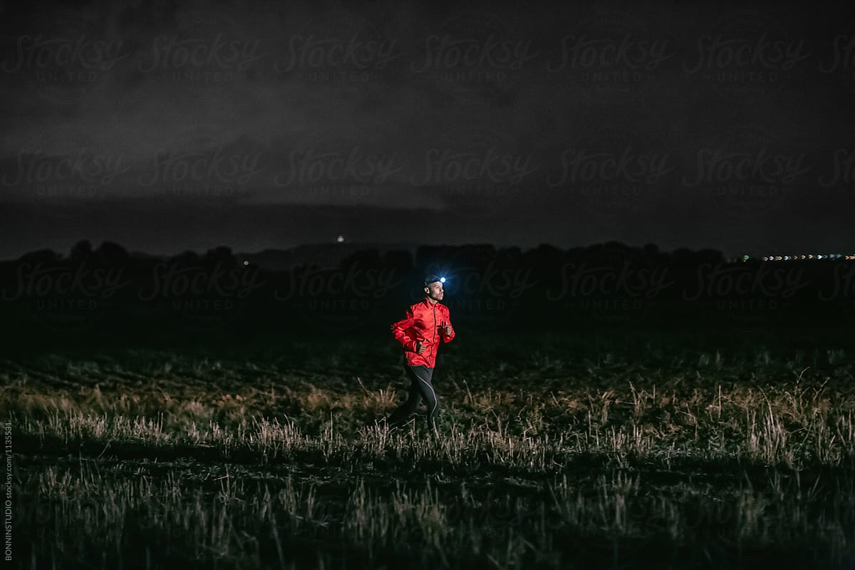 Man running on a field path at night.