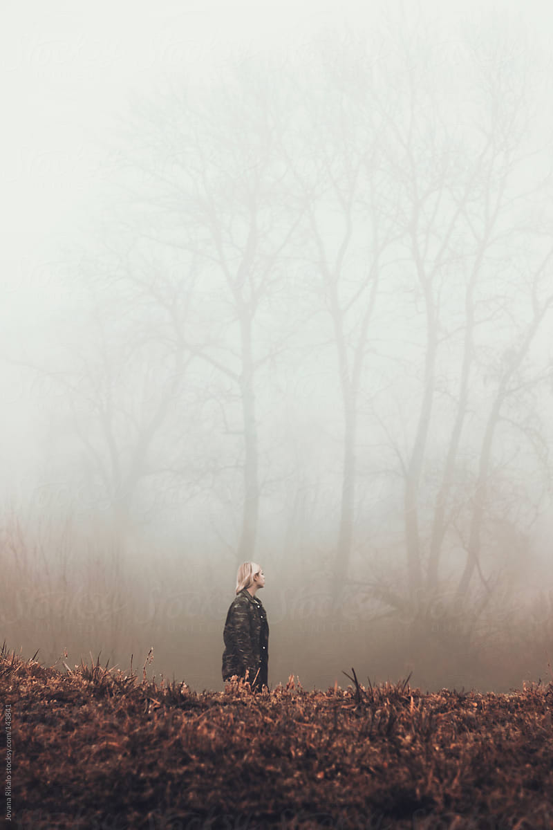 A young girl walking in a field with fog