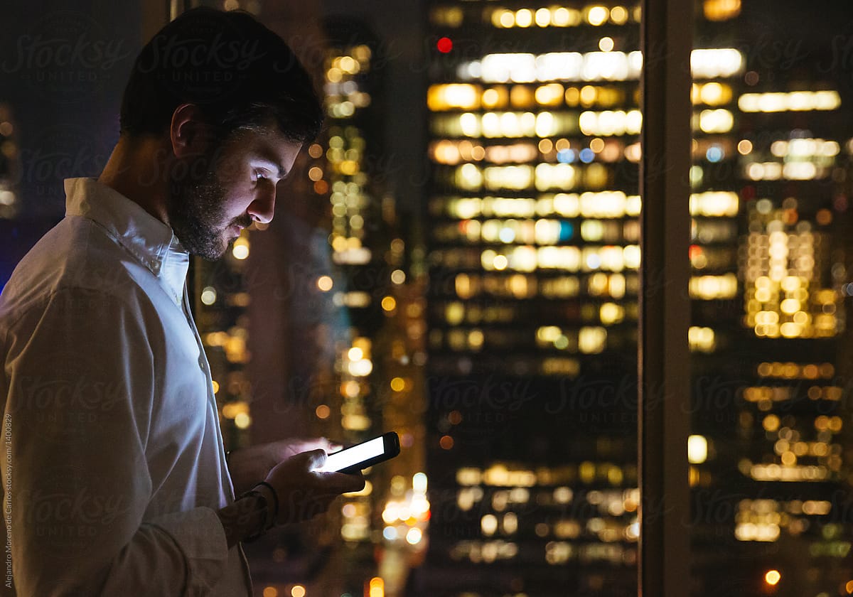 Young businessman checking his phone on an office at night