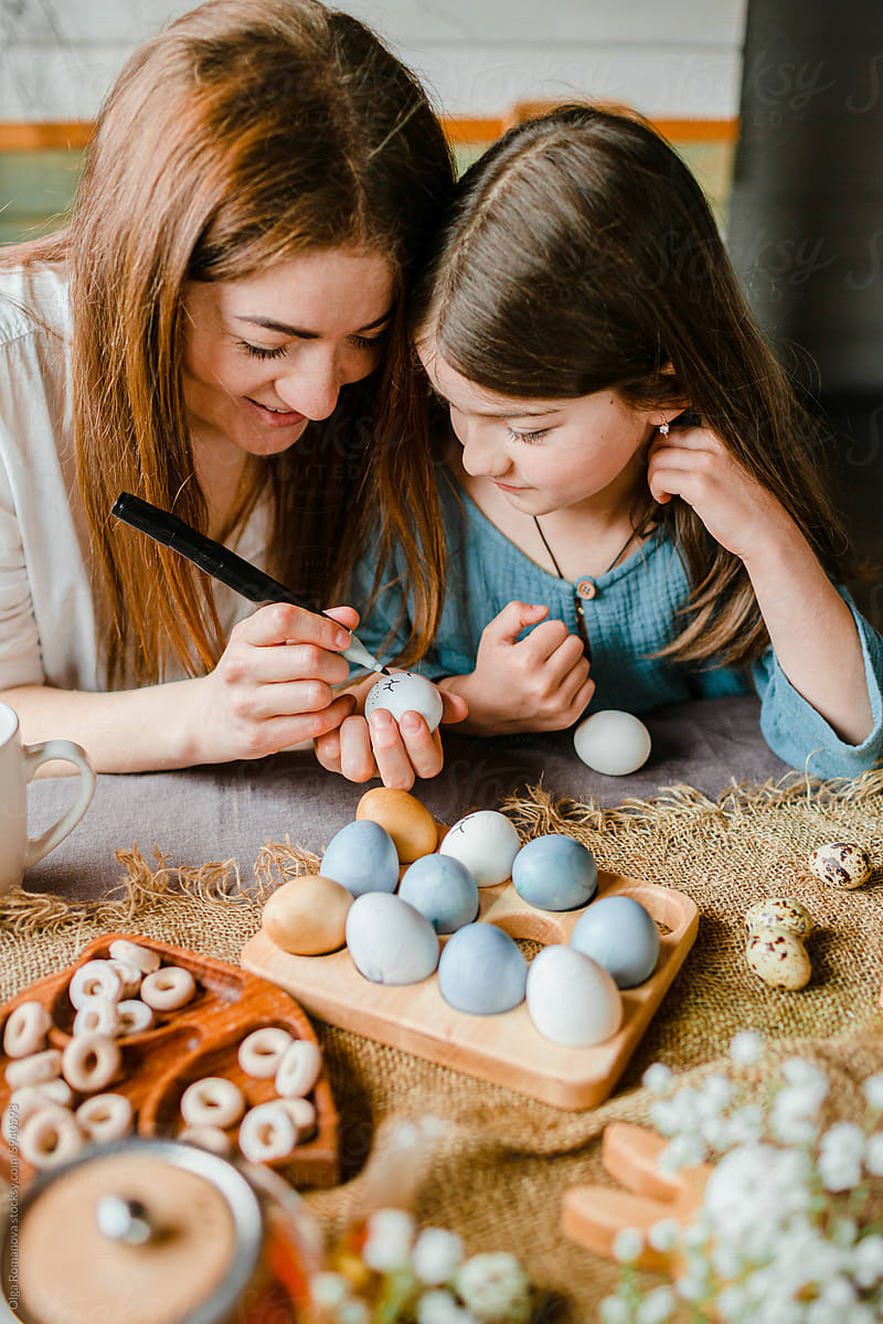 Family Easter fun with mother and little daughter painting eggs