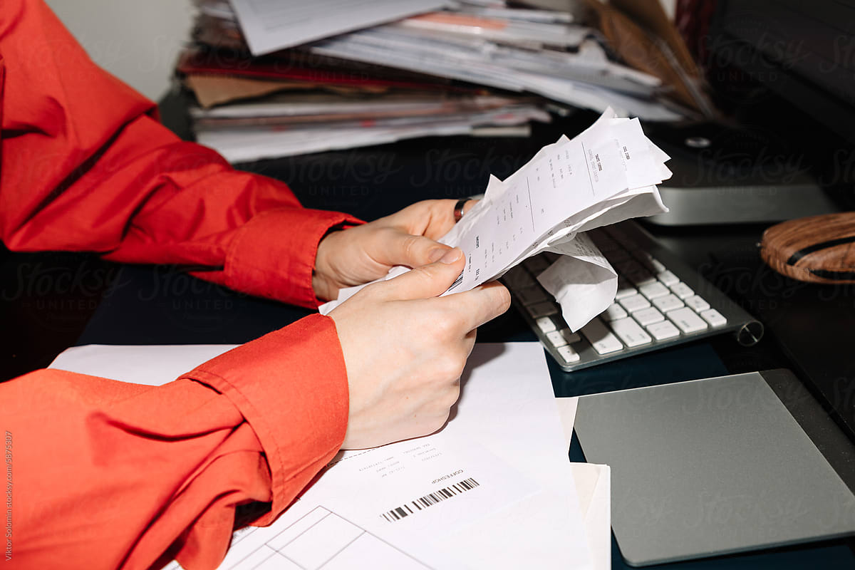 Crop faceless woman manages a stack of receipts in office