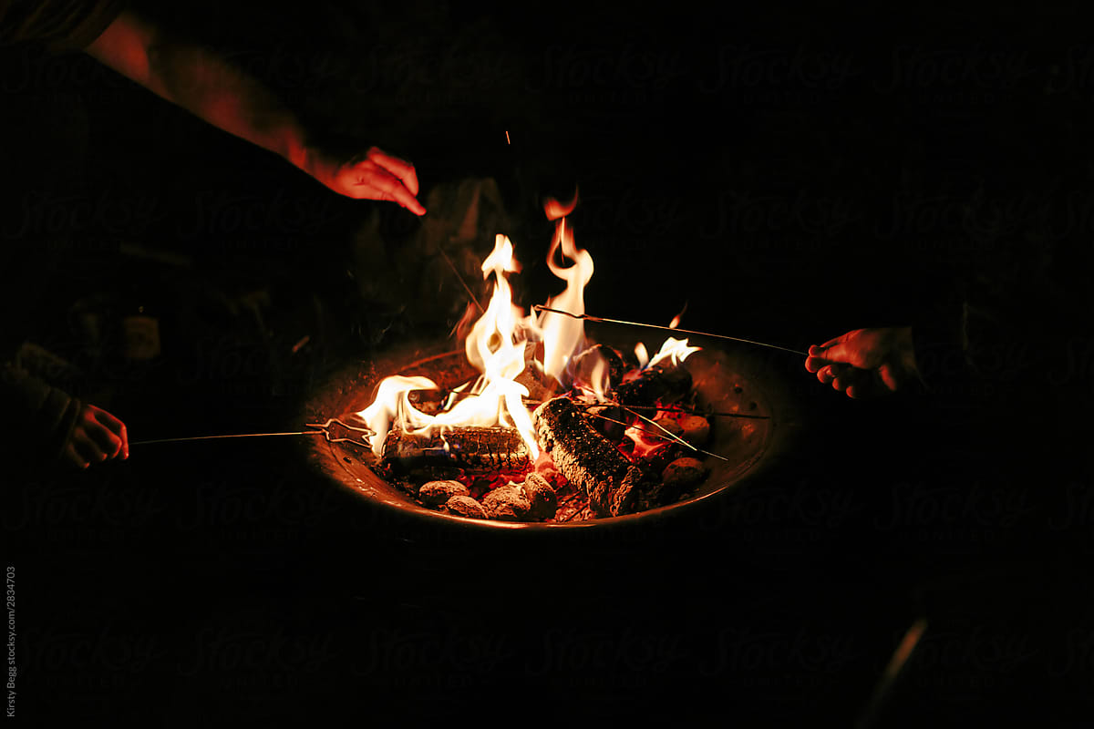 Family lighting sparklers in log fire in firepit