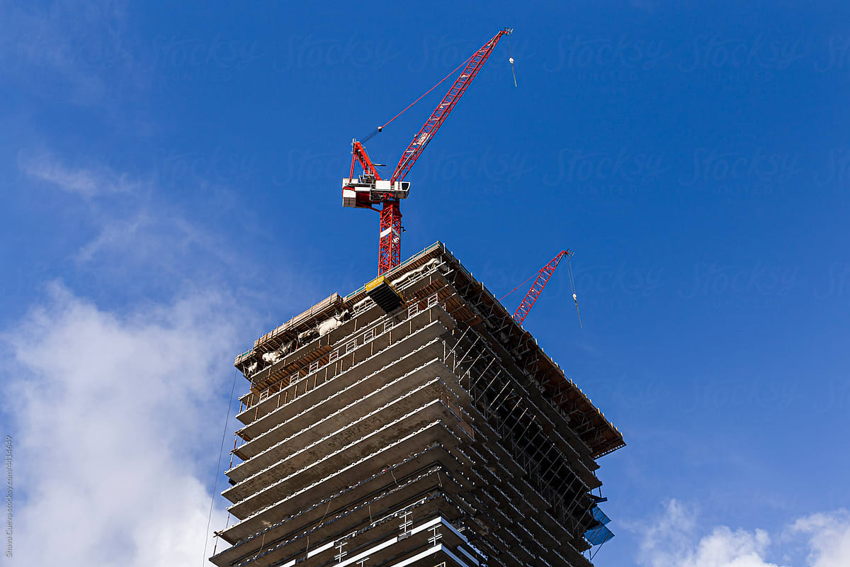 A building under construction with red cranes