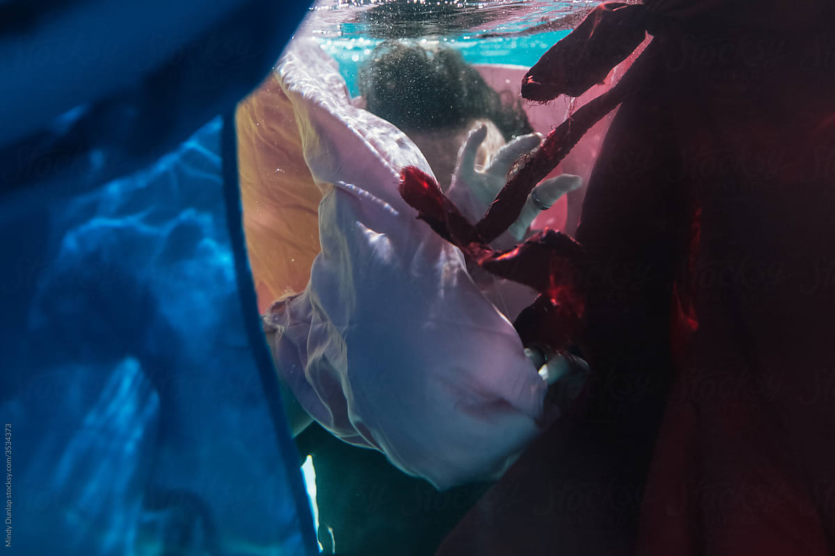 Portrait of a man underwater behind flowing sheets