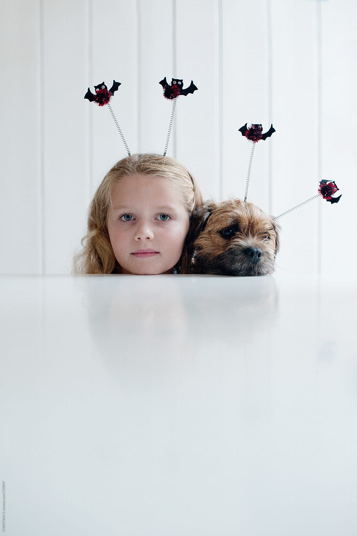 Girl and her dog sitting at the table with Halloween deely boppers