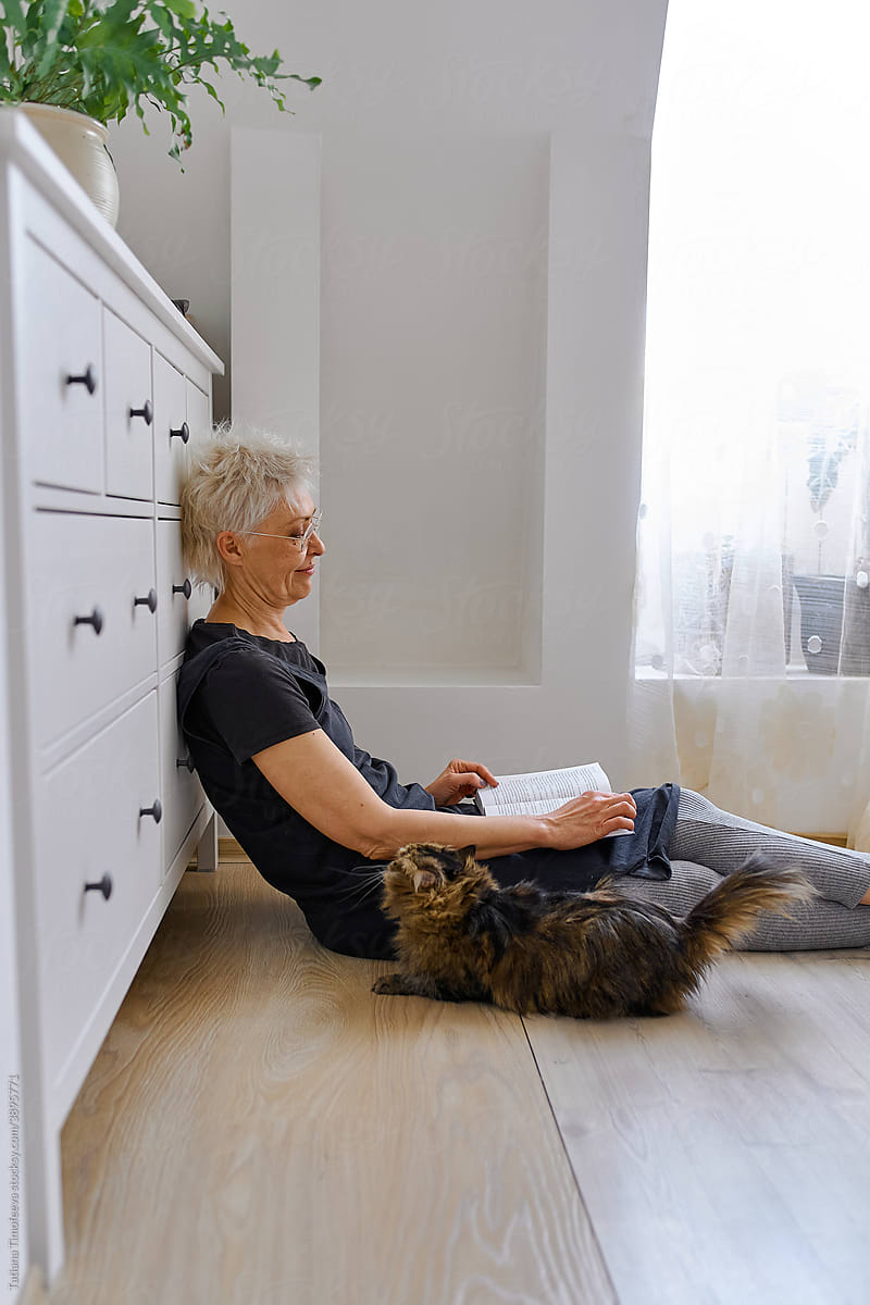 senior elderly woman petting pet cat at home bedroom