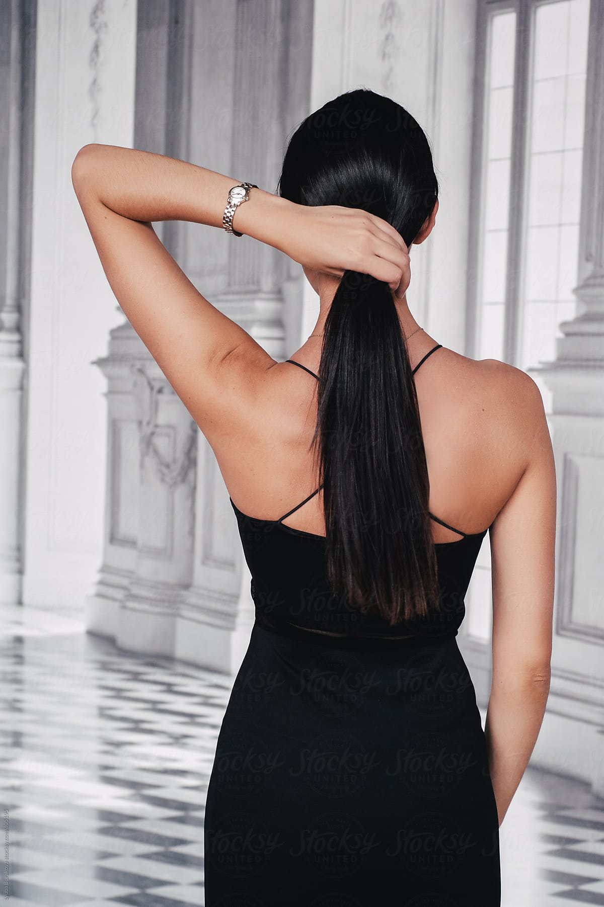 Back view of the woman holding her hair in a tail