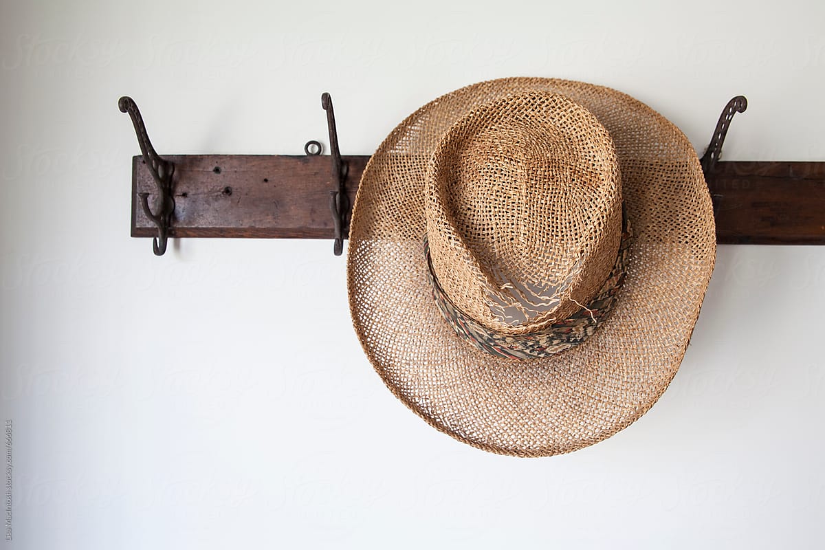 Old straw hat on antique coat rack hook
