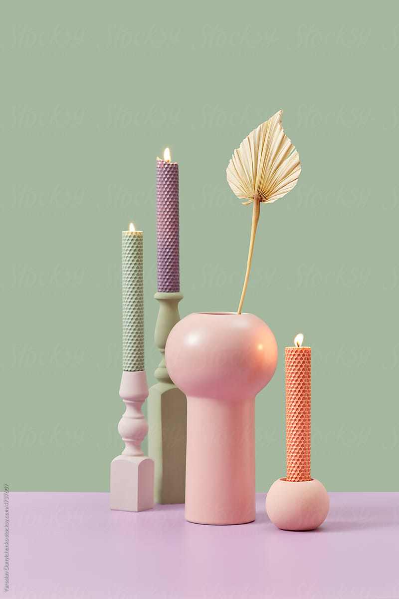 Candles with candlesticks and plant in vase.