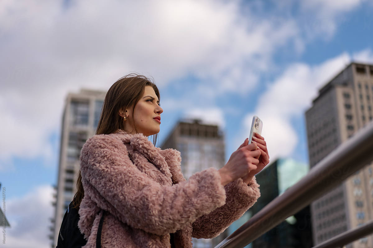 Woman uses her smartphone to take pictures in the city