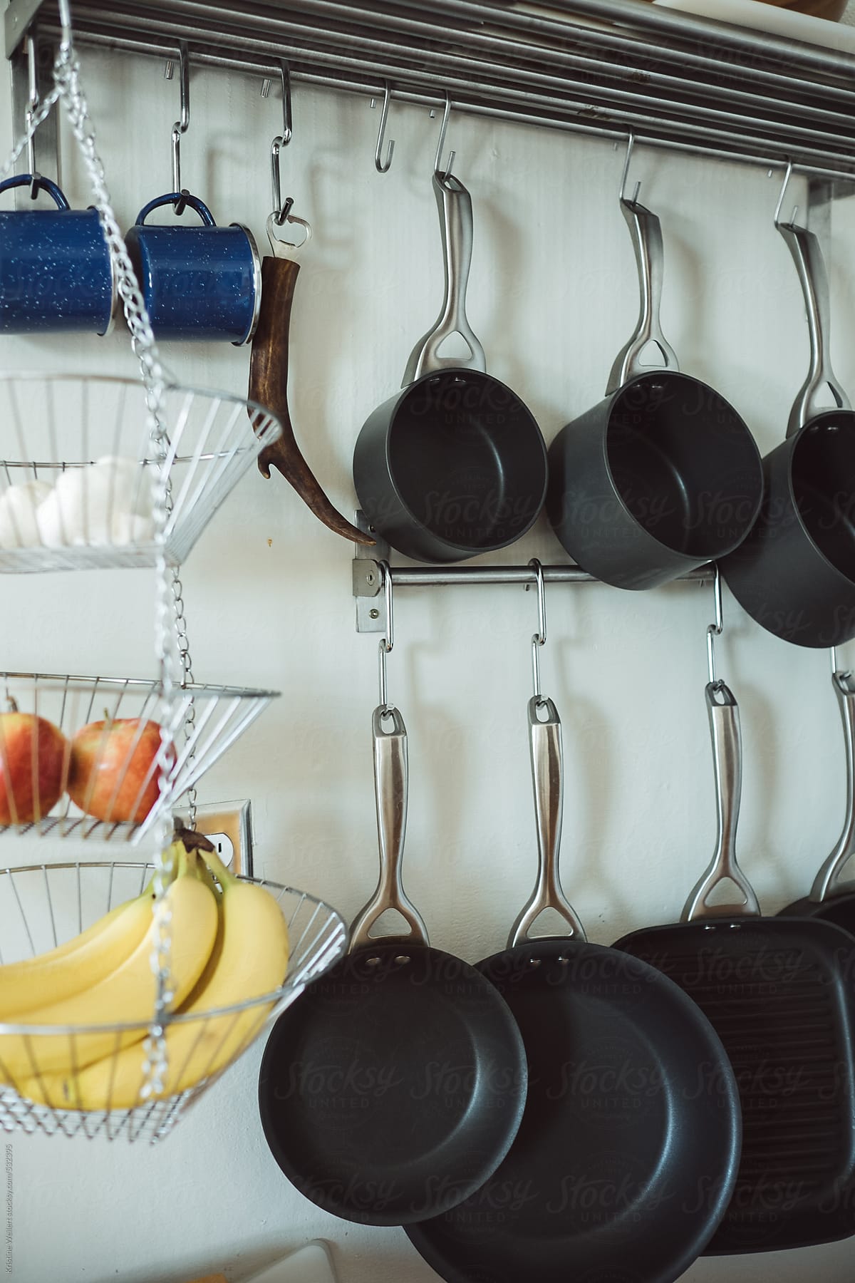 Kitchen pots and pans and other utensils organized and hanging on a wall