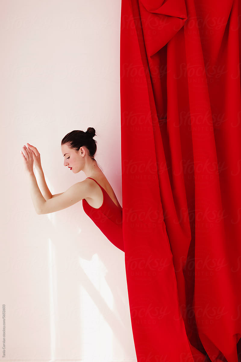 Slim young woman hiding waist downwards behind curtain