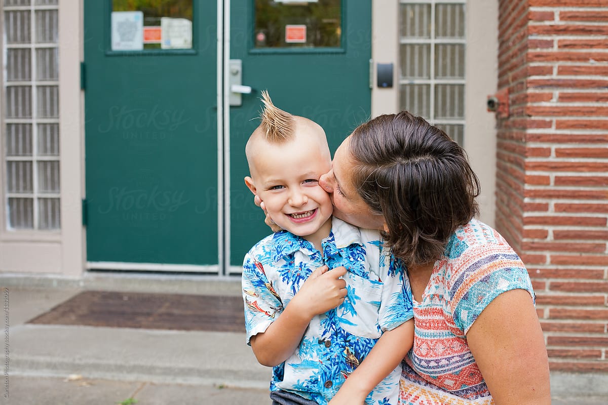Mom kissing five year old boy on the cheek on the first day of school
