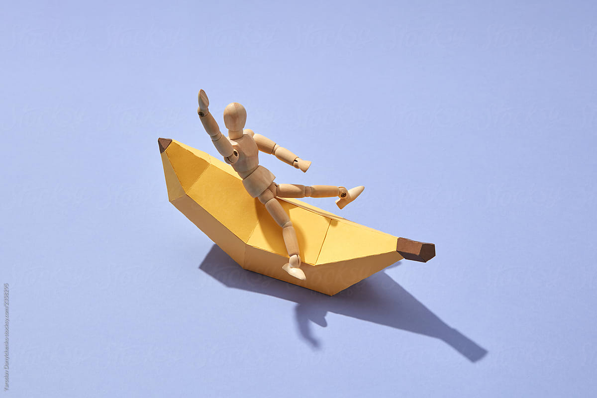 A miniature wooden doll on a paper handcraft banana