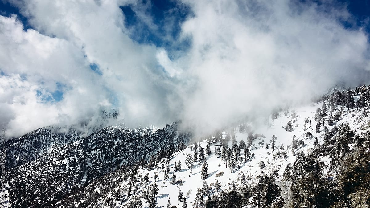 Clouds Rolling Over Snowy Ridge with Blue Sky