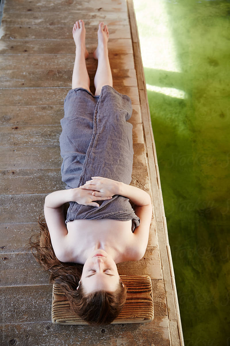 Woman meditating on wood planks at Japanese hot springs