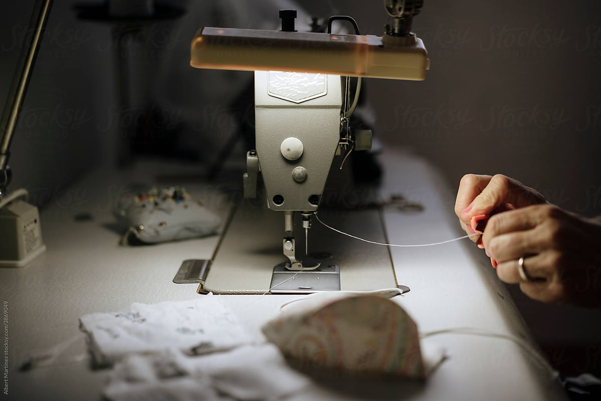 Hands on a sewing machine under dim light