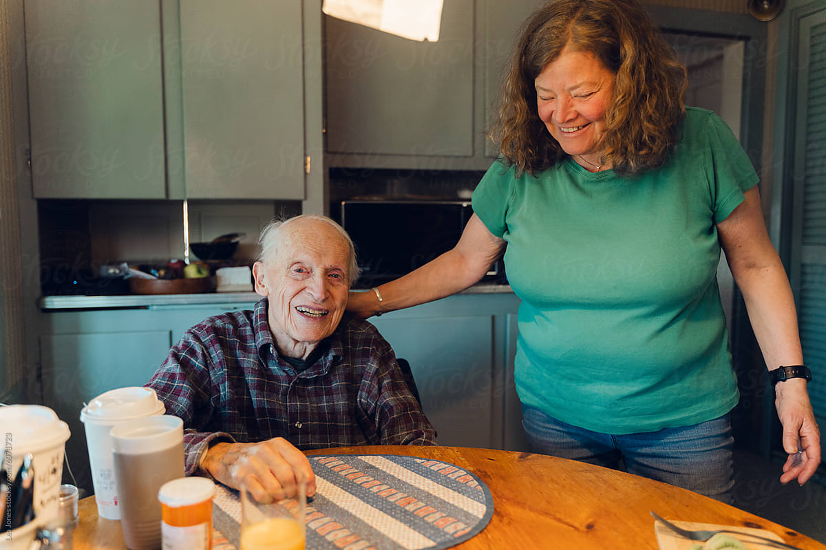 portrait of happy elderly man  with his daughter   in his kitchen